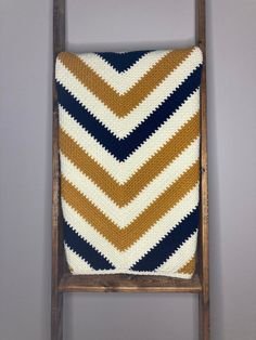 a wooden chair with a knitted cushion on it's back, against a gray wall