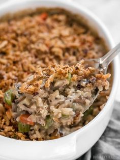 a close up of a spoon full of food with rice and vegetables in it on a table