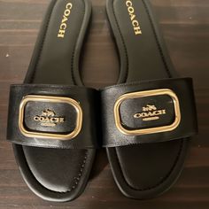 Brand New Coach Slippers. Never Worn. Comes With Original Box Classic Coach Sandals For Summer, Designer Black Slides With Buckle Closure, Coach Leather Slides With Round Toe, Classic Black Slides With Flat Heel, Classic Black Flat Heel Slides, Chic Black Flat Slides, Coach Flat Slides With Removable Insole, Coach Slides With Branded Insole And Round Toe, Coach Black Sandals With Cushioned Footbed