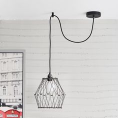 a white brick wall with a black wire light fixture hanging from it's side