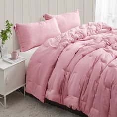 a bed with pink comforters and pillows on it