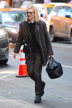 a woman walking down the street with a handbag in her other hand and wearing black shoes