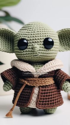 a crocheted baby yoda doll sitting on top of a table