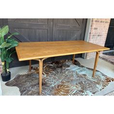 a wooden table sitting on top of a rug in front of a garage door next to a potted plant