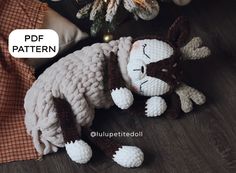 a crocheted sheep laying on the floor next to a christmas ornament