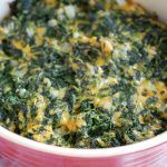 a bowl filled with spinach and cheese on top of a table