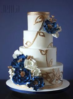 a three tiered wedding cake with blue and white flowers on the top, is displayed