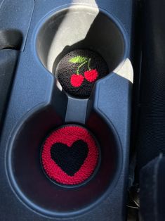 two black and red balls with cherries on them sitting in a car cup holder