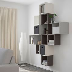 a living room filled with furniture next to a white vase and wall mounted book shelf