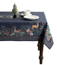 a table cloth with deers and flowers on it, next to a white cup