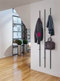 there is a coat rack with two coats hanging on it and a purse next to it