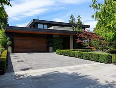 a modern house with hedges and trees around it