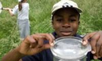 a young man holding a silver cup in front of his face while two other people stand behind him