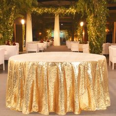 a gold table cloth on top of a round table in a room with white chairs