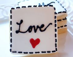 two cookies with the word love spelled in black and white icing on top of each cookie