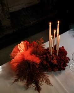 a table topped with candles and flowers on top of a white cloth covered tablecloth