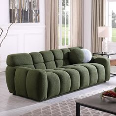 a living room with a large green couch and coffee table in front of the window