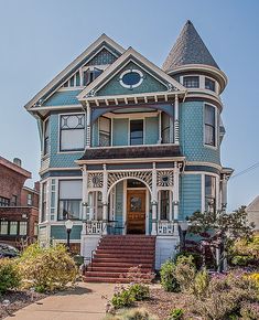 a blue victorian style house with stairs leading up to the front door