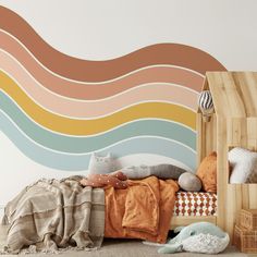 a bed with pillows and blankets on it in front of a wall painted with waves