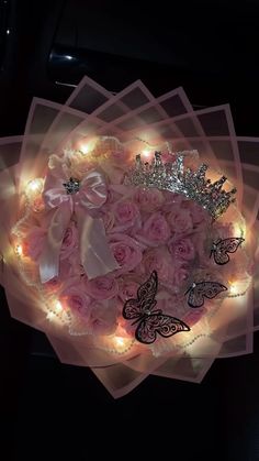 a bouquet of pink roses with lights in the shape of a tiara and butterflies