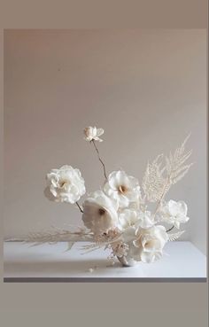 white flowers are in a vase on a table