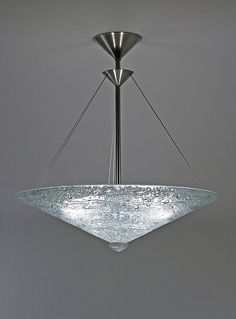 a large glass bowl hanging from the ceiling in a room with grey walls and flooring