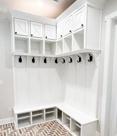 a mud room with white cabinets and benches on the wall next to a tiled floor