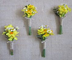 four bouquets of yellow and white flowers are arranged on a tableclothed surface