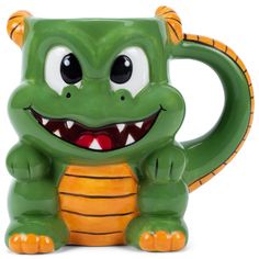 a green and orange ceramic toy with big teeth on it's face, sitting in front of a white background