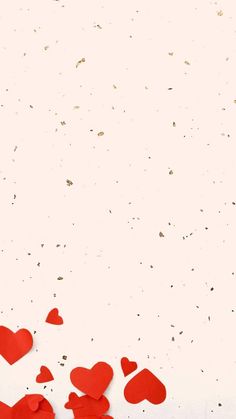 red paper hearts on white background with confetti scattered around them and space for text