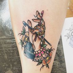 a woman's foot with a tattoo on it that has scissors and flowers around it