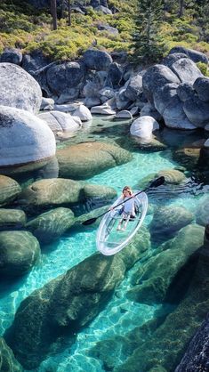 a man riding a paddle board on top of a body of water next to rocks