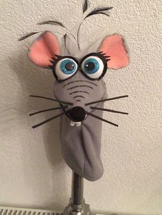 a stuffed mouse with big blue eyes on top of a metal pole in front of a white wall