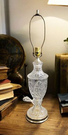 a glass lamp sitting on top of a wooden table next to an old fashioned book