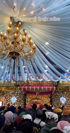 a large group of people standing in front of a chandelier and some lights