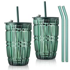 two green glass tumblers with straws next to each other