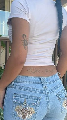 the back of a woman's jeans with tattoos on her lower half and arms