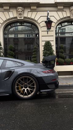 a grey sports car parked in front of a building