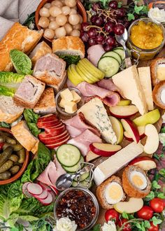 a platter filled with assorted meats, cheeses and vegetables next to crackers