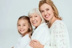 an older woman and two younger women hugging each other in front of a white background