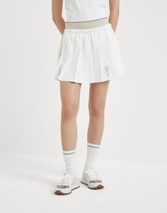 Pleated techno poplin mini skirt with tennis logo The sporty yet elegant feel of the world of Tennis inspires a selection of creations that enrich the Women's collection. The techno poplin pleated skirt, inspired by the style of the designs worn on the sidelines, features a practical elastic waistband in contrasting colors and a pair of built-in shorts that provide added comfort. The racket embroidery detail reinterprets the Brunello Cucinelli logo and crest with a personalized touch. Sporty Mini Tennis Dress, White Sporty Relaxed Mini Skirt, Sporty White Relaxed Mini Skirt, White Relaxed Sporty Mini Skirt, Classic White Tennis Skirt, Classic White Mini Tennis Skirt, Sporty White Cotton Skirt, Classic White Tennis Skirt For Spring, White Tennis Mini Skirt For Spring