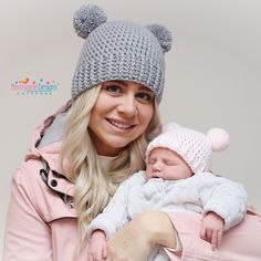 a woman holding a baby wearing a knitted bear hat