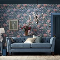 a living room with blue walls and floral wallpaper on the walls, two couches and a lamp