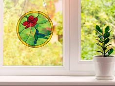 a potted plant sitting on top of a window sill next to a stained glass