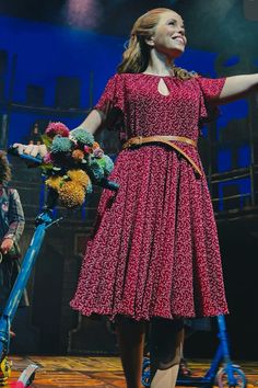 a woman in a red dress standing next to a blue scooter with flowers on it