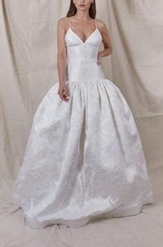 a woman in a white wedding dress posing for the camera with her hands on her hips