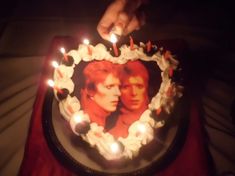 a person lighting candles on a cake with the image of two people