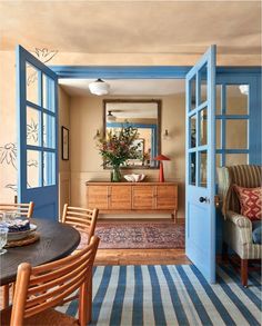 an open door leading to a dining room with blue trim on the walls and wooden furniture