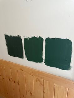 three green paint samples are on the wall next to a radiator