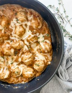 a skillet filled with meatballs covered in gravy next to a napkin